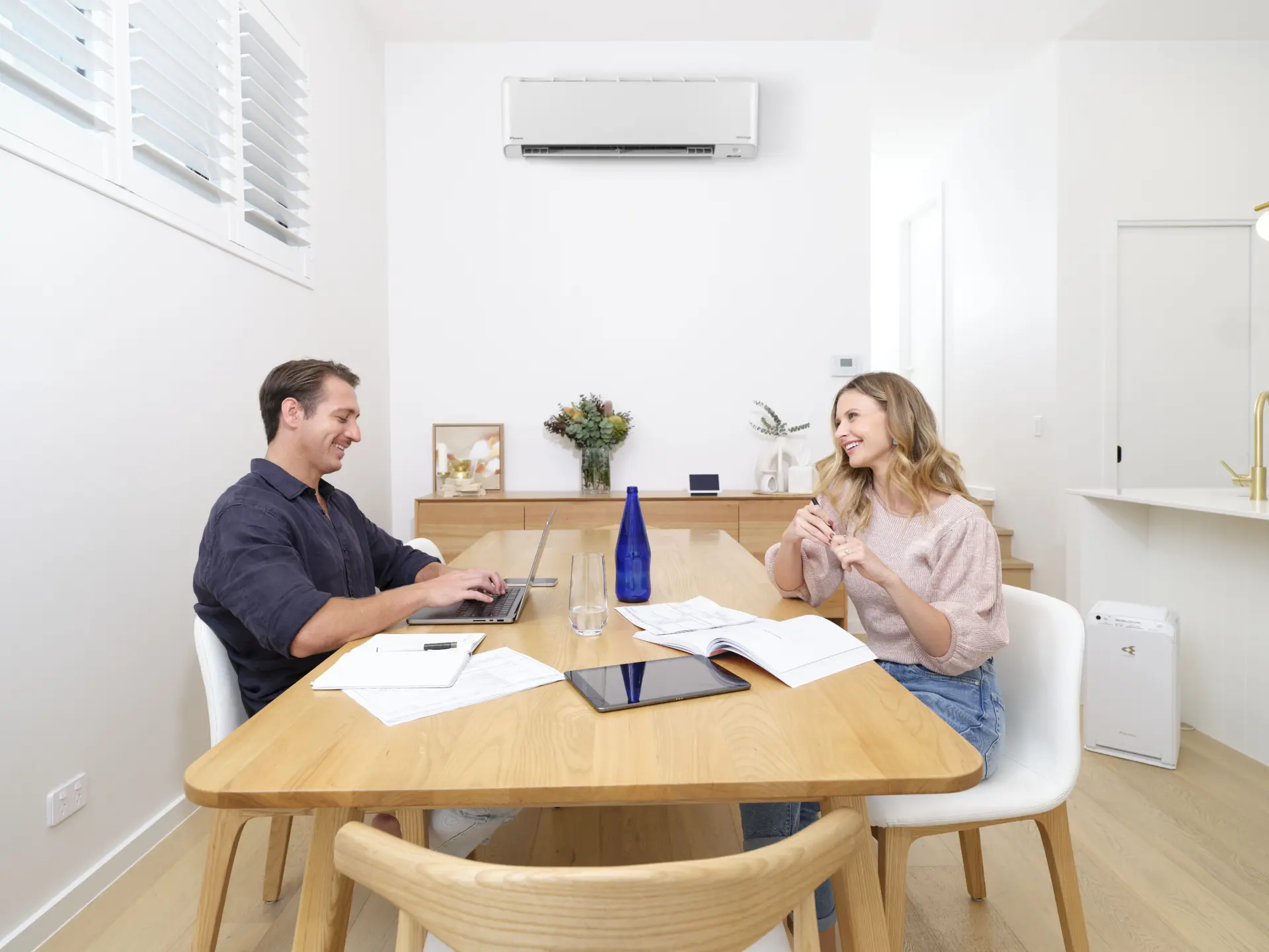 Couple working at dining table beneath wall-mounted air conditioner