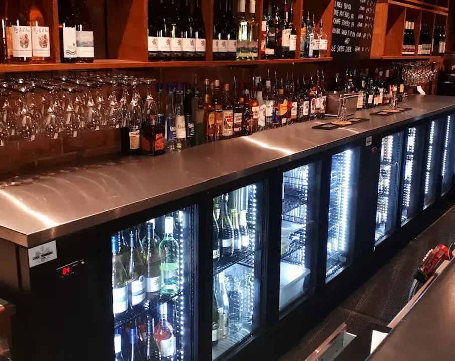 Well-stocked bar counter with wine, spirits and glass-door fridges